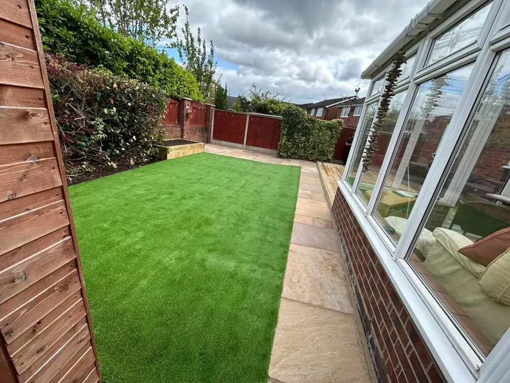 Narrow garden with artificial lawn, a stone path, planting and timber fencing