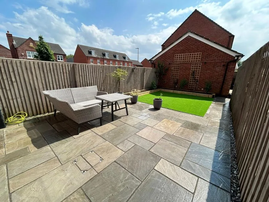 Kingsmead rear garden with stone patio, outdoor sofa and artificial lawn