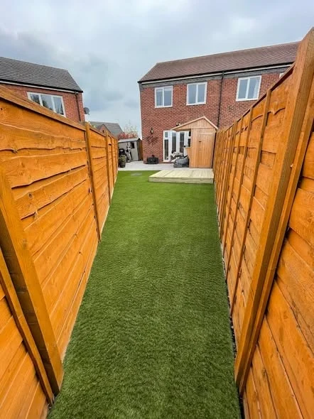 Artificial grass through a rear garden enclosed by timber fencing