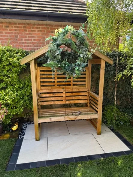 Timber garden seat on a small porcelain paved area beside the new lawn