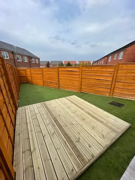 Timber deck beside artificial grass in a fenced rear garden